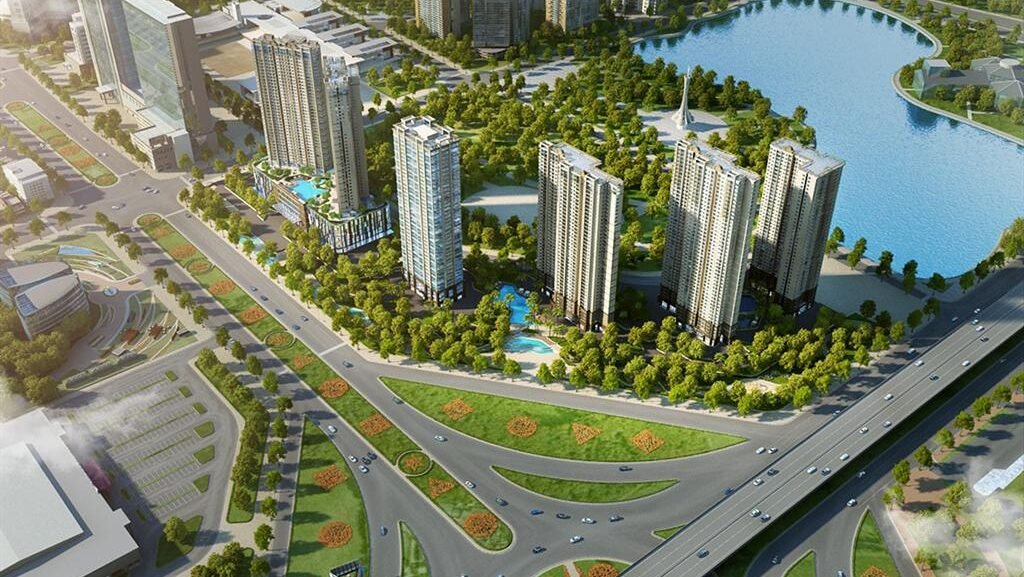 Aerial view of a modern urban development with tall residential towers surrounding a blue lake, lush trees, and curved roads and interchanges nearby.