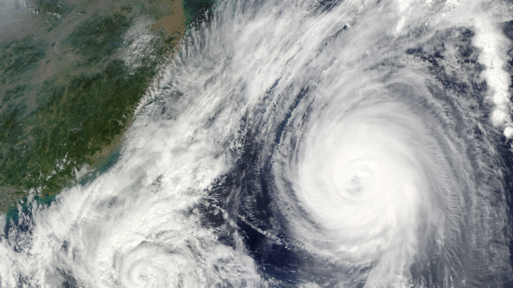 Satellite image of a large hurricane with a clear eye approaching a green coastline along the left edge of the image.
