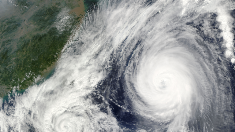 Satellite image of a large hurricane with a clear eye approaching a green coastline along the left edge of the image.